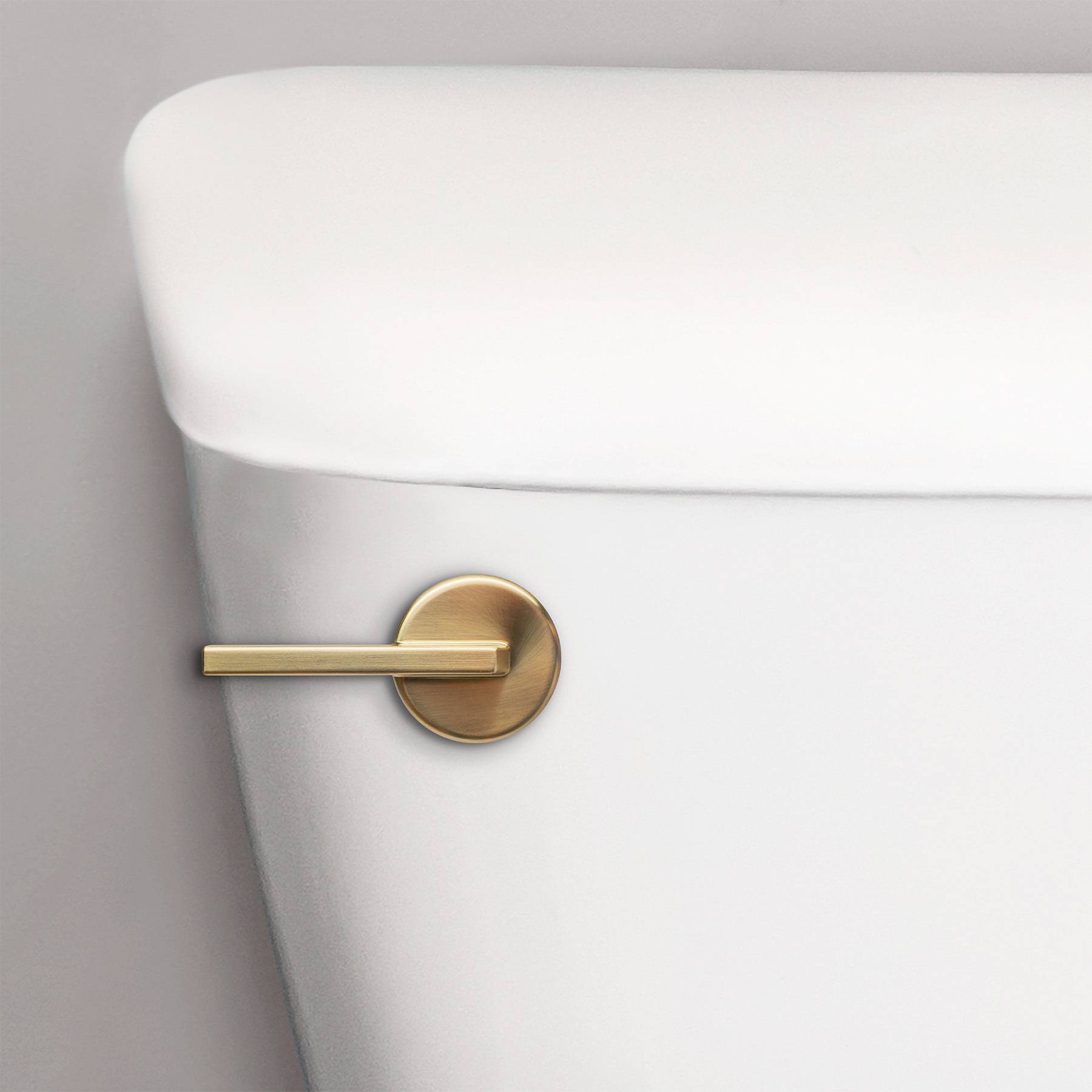 brushed gold contemporary toilet handle on a toilet tank